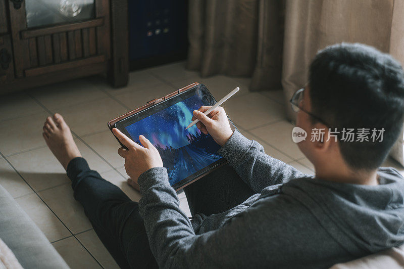 一位亚洲华人中年男子在家用平板电脑画画