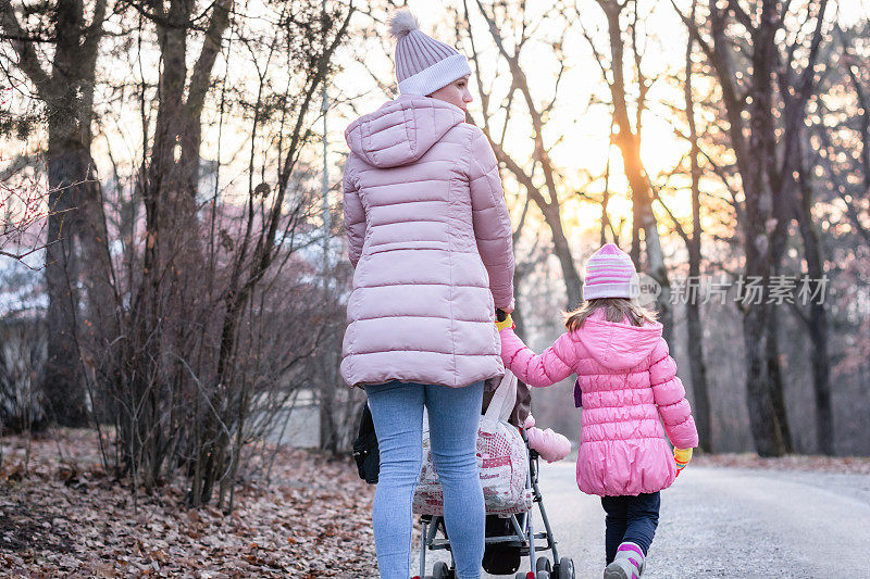 年轻的妈妈和她的孩子们在公园里散步。