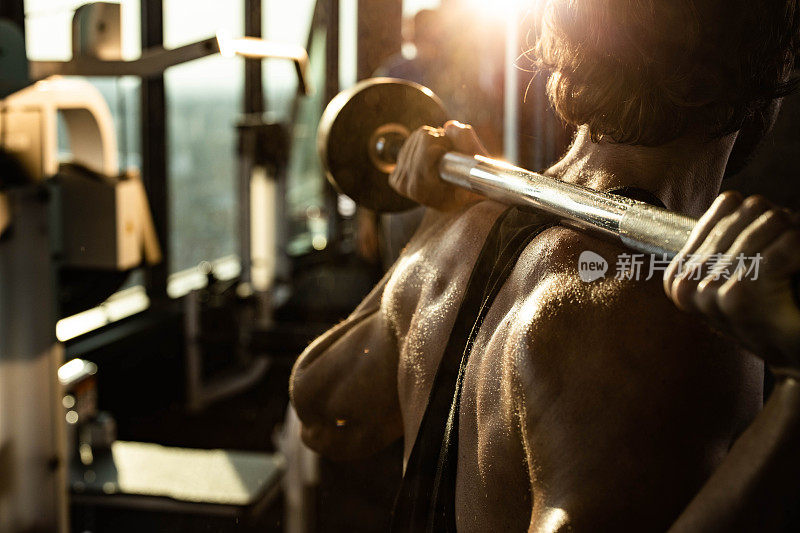 近距离的出汗肌肉建设运动员做背部练习杠铃在一个健身房。