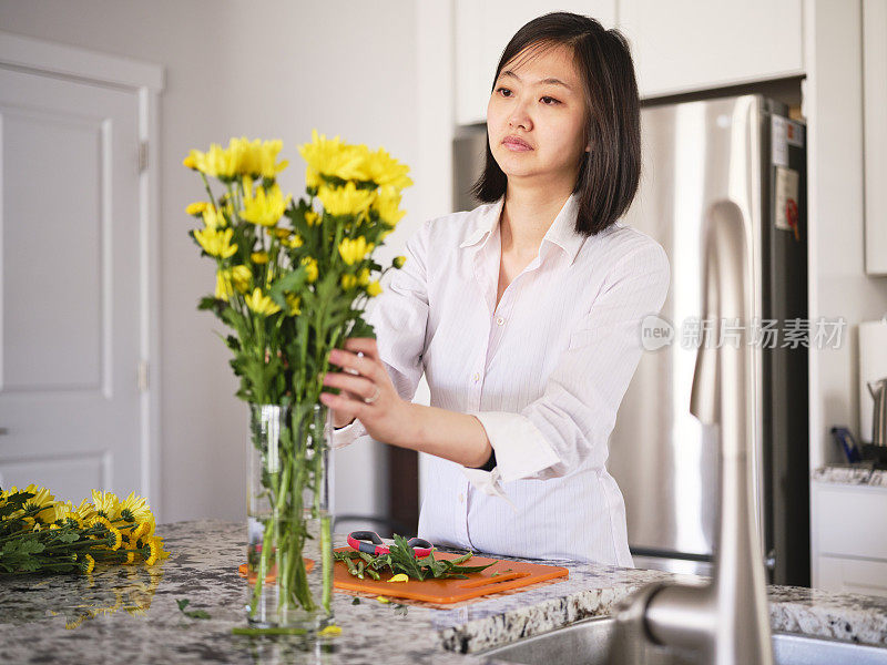 亚洲妇女在她的家里插花