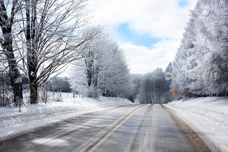 结冰的道路两旁是白雪覆盖的树木