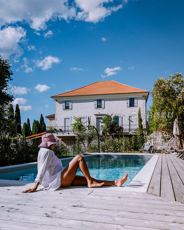 在法国阿尔代什有木制甲板和游泳池的法国度假屋。在法国南部的度假屋豪华度假期间，女人放松与木制甲板的游泳池