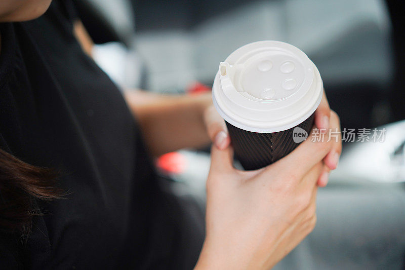 年轻女子在车里拿着咖啡杯