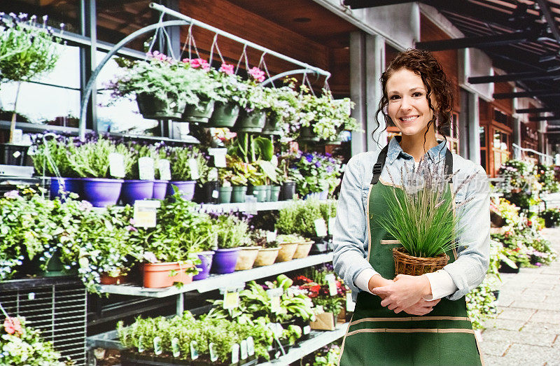 白人女主人园艺穿着衬衫和持有植物