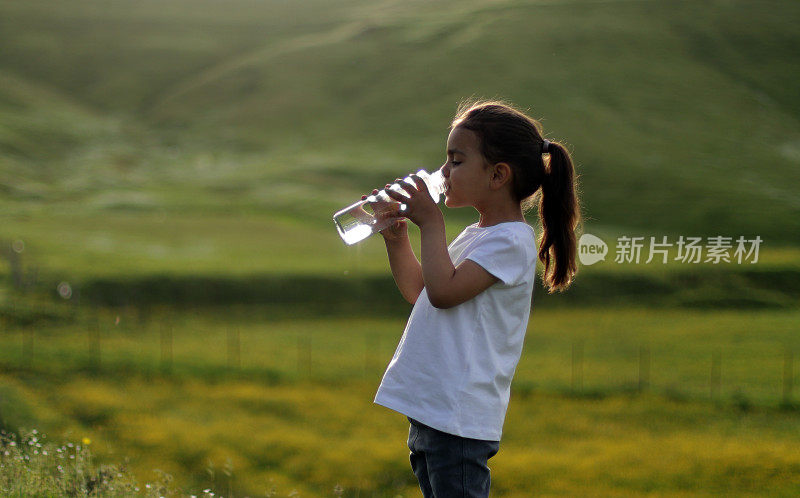 小女孩喝瓶子里的水