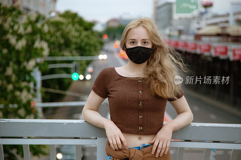 快乐的女孩戴着防毒面具在欧洲城市的桥上。