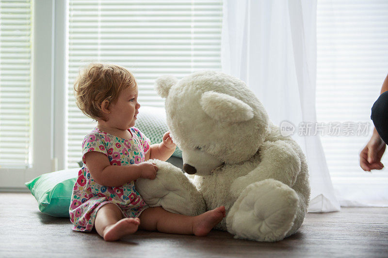小女孩在玩一个大泰迪熊玩具