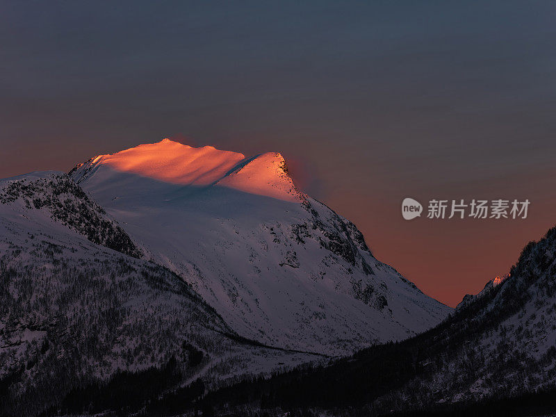 第一道晨光照亮了挪威Senja的Bergsbotn山顶。