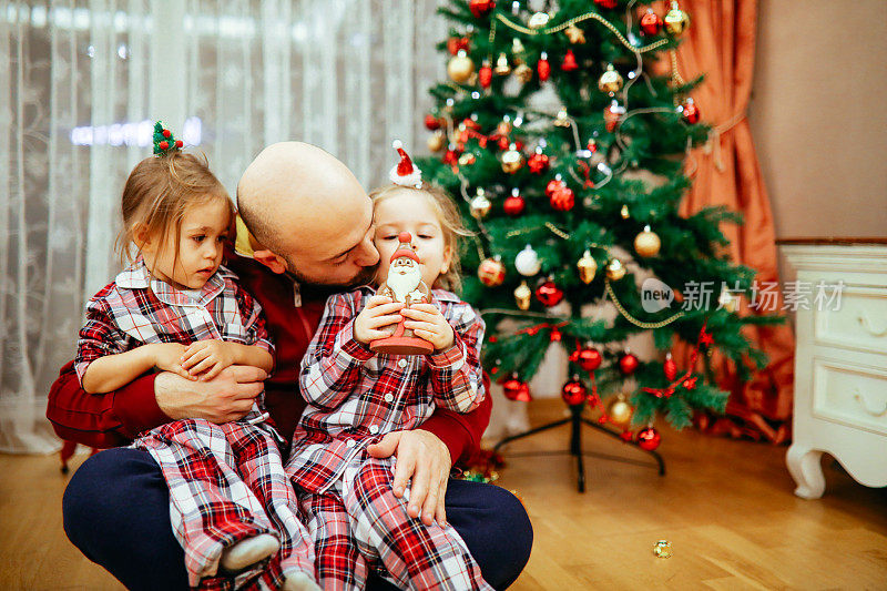 肖像快乐的父亲拥抱他的女儿在圣诞树前在家里