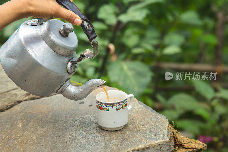 将热茶倒入白色陶瓷茶杯中