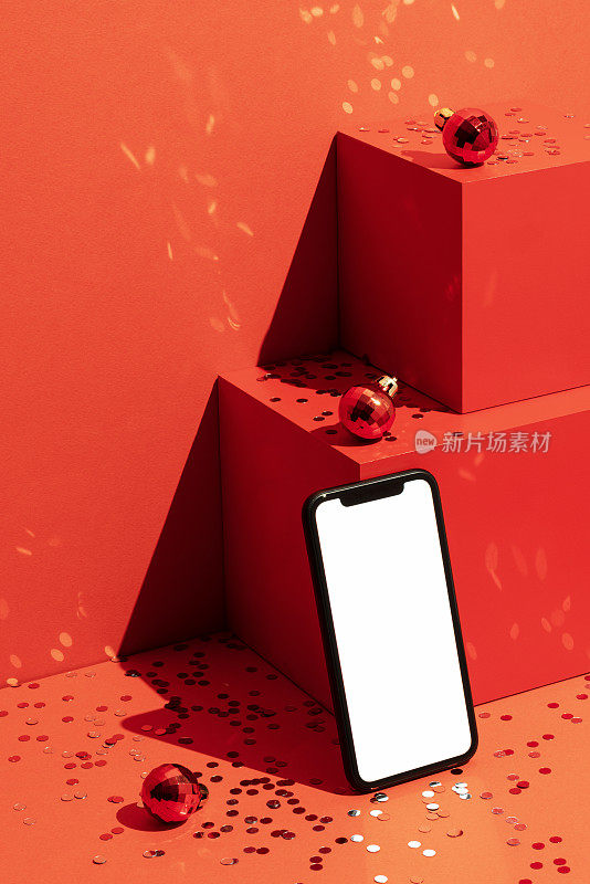 智能手机模型，红色背景上的圣诞球和五彩纸屑模板