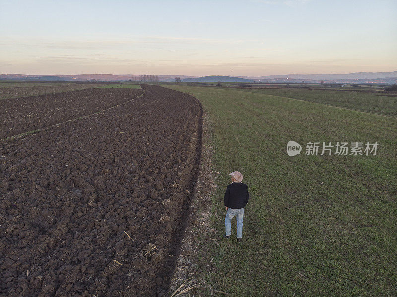 一个成年的农民在他的农场里在早春的时候耕种田地。鸟瞰图。