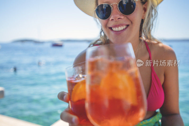 一对夫妇在海边的甲板上喝着鸡尾酒敬酒。