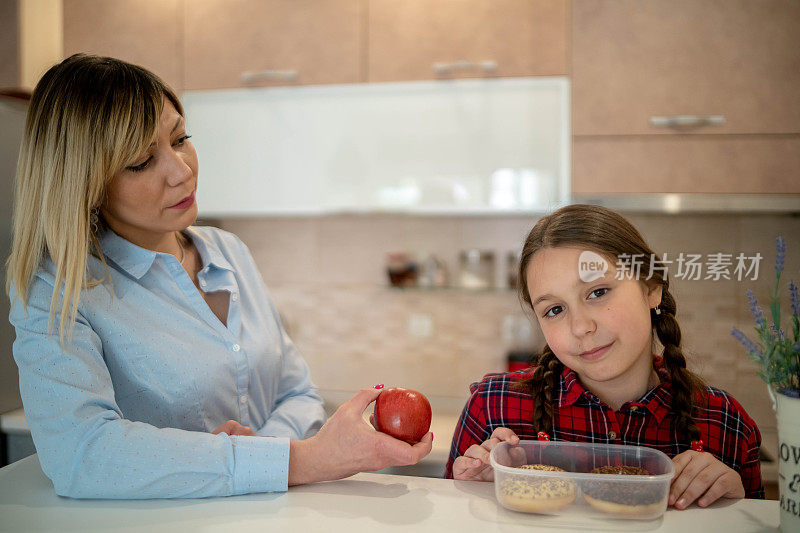 妈妈送女儿去学校，给她一个苹果。