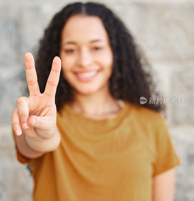 一名女子站在外面，举着和平标志