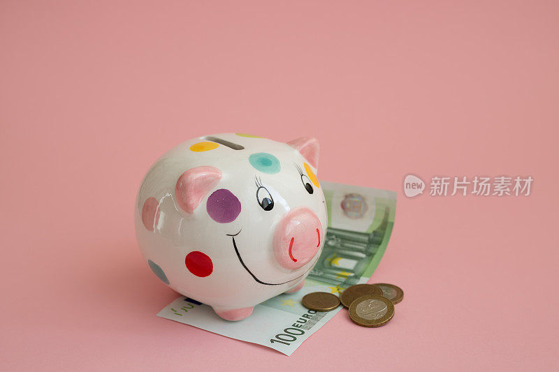 小猪储蓄罐上画着五颜六色的圆点花纹。粉红色背景上的硬币和现金。白俄罗斯卢布。存钱，投资未来。欧元区的货币。
