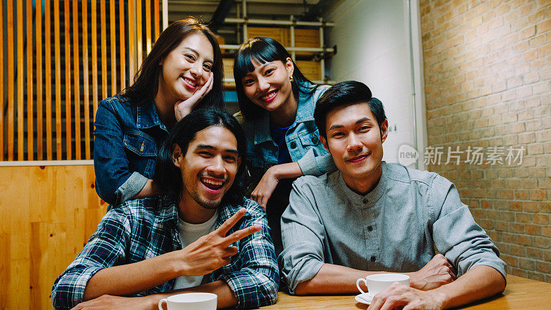 一群快乐的年轻亚洲朋友有一个伟大的时间和看相机，自拍坐在一起的咖啡馆餐厅。