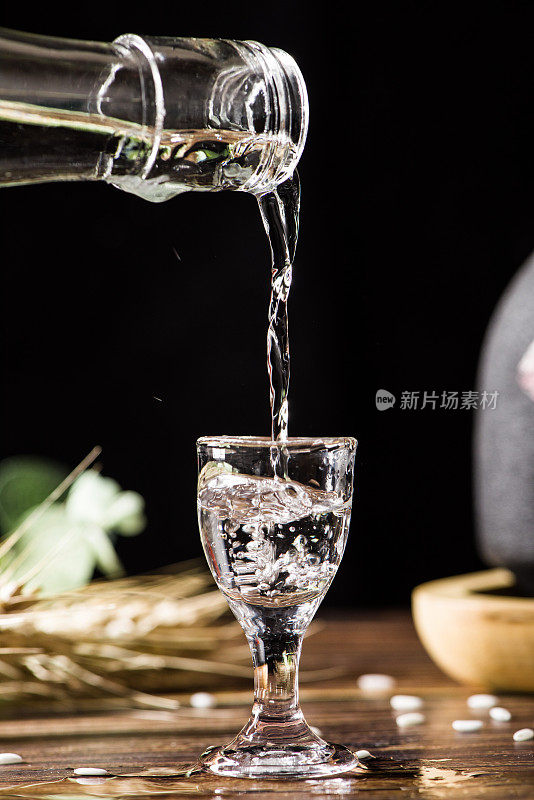 中国白酒，烈酒饮料从一个瓶子倒进一个玻璃杯的木材背景