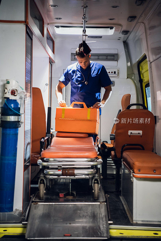 一位穿着医疗制服的年轻医生在救护车上打包他的医疗包