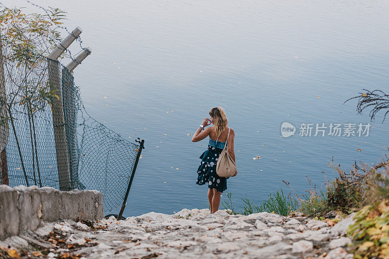 女人在石道上向湖边走去