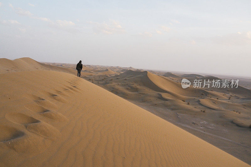 一个面目全非的人独自走在沙漠的沙丘上