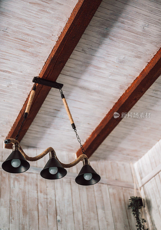 一套由三个黑色宽金属极简吊灯组成，挂在天花板上的绳子上