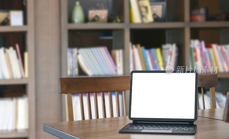 在图书馆的木桌上用魔法键盘模拟空白白色屏幕平板电脑。