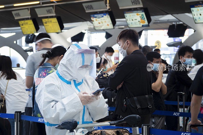 在泰国曼谷素万那普机场，亚洲乘客穿着防护服，在航班前办理登机手续。