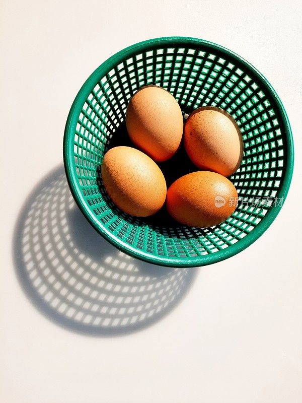 棕色鸡蛋在深绿色篮子-白色背景。