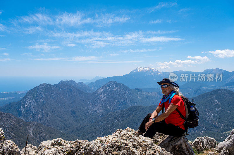 背包客坐在岩石上看山，看山谷