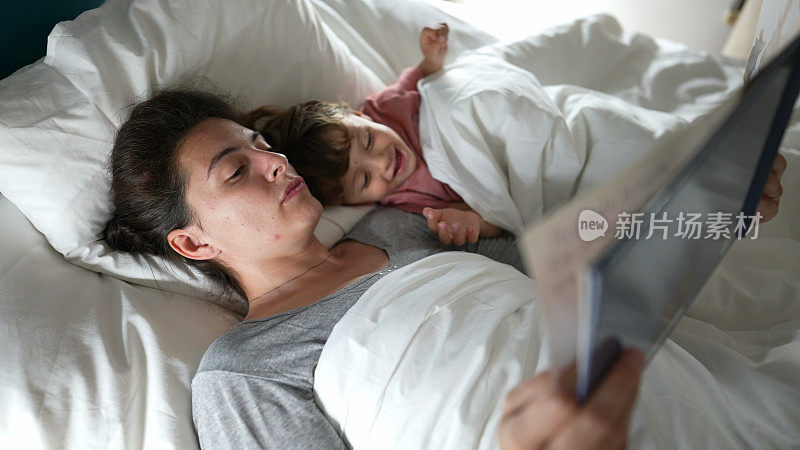 睡前，妈妈抱着孩子躺在床上读睡前故事