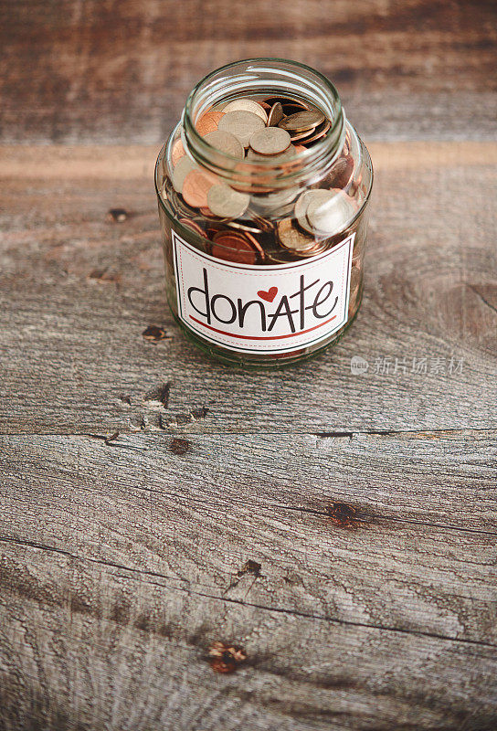 木制背景的玻璃罐里装满了慈善捐赠的美元