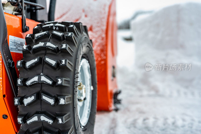 选择性聚焦在吹雪机轮胎与散焦漂移的雪在背景..