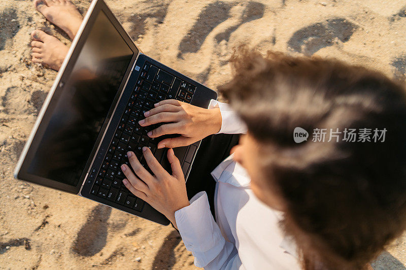 年轻女子在海滩上使用笔记本电脑