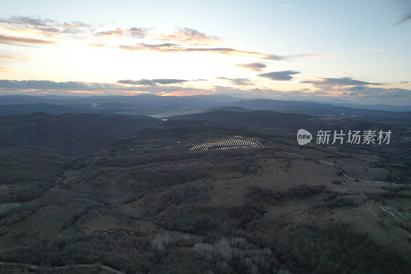 日落时的太阳能电池板和风力涡轮机。可再生能源