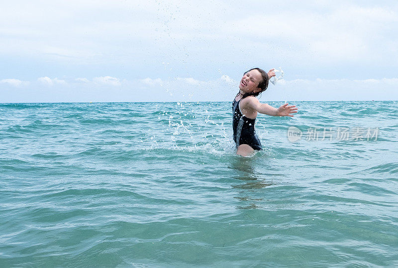 7岁的白种人女孩在海里游泳并溅起水花。在沙滩上休息，感受一下激情的飞溅。
