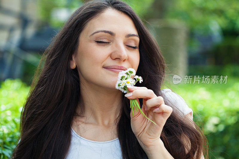 美丽的年轻女子闻着花香