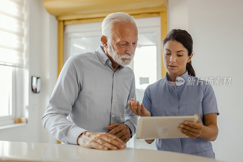 医生拿着平板电脑和医院里的老年病人谈话