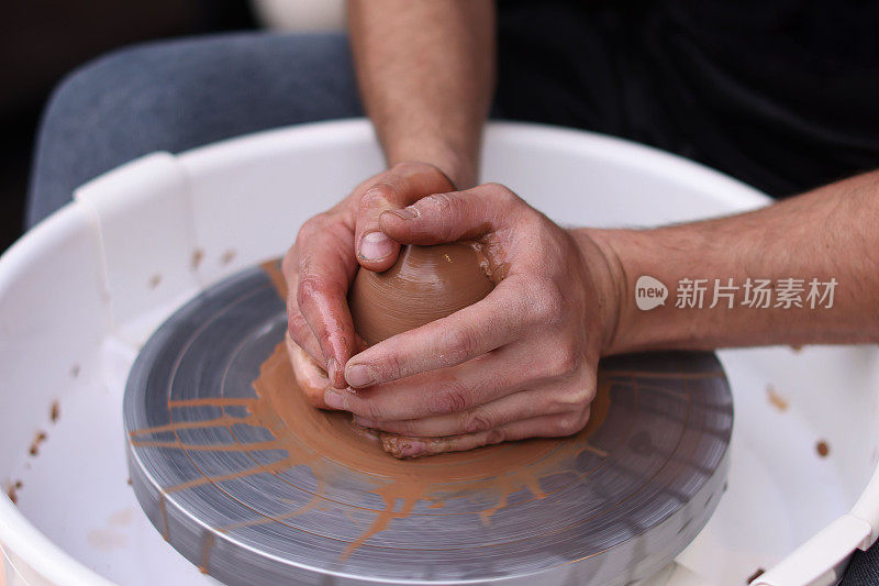 一名陶工在陶瓷工作室的陶工转盘上摆弄陶瓷器皿