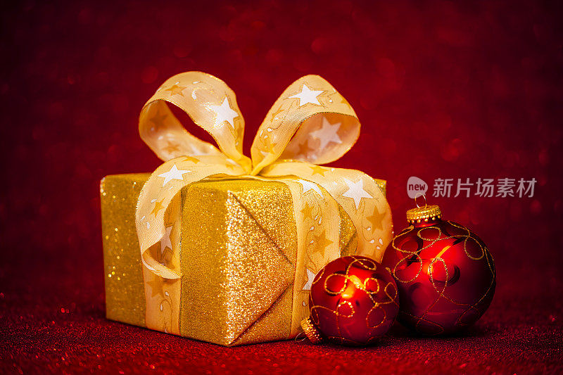 金色礼盒与红色圣诞小玩意在红色闪闪发光的背景
