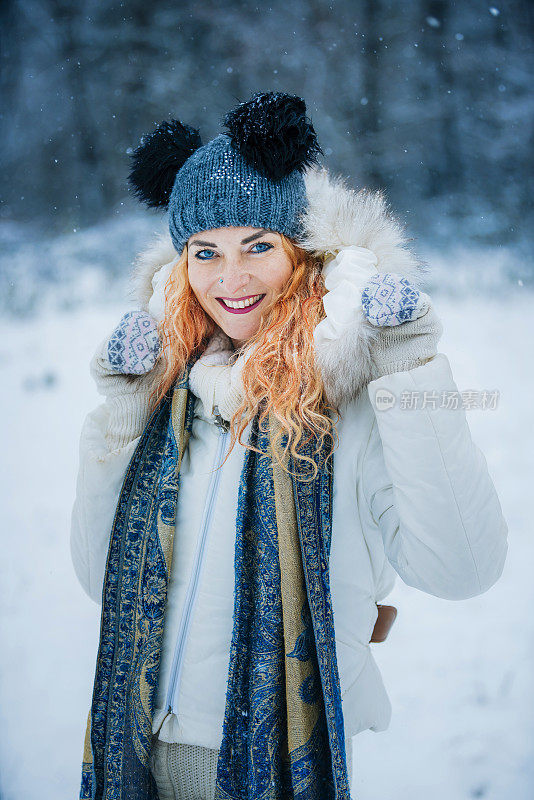 幸福的女人在冬天森林附近的白雪皑皑的草地