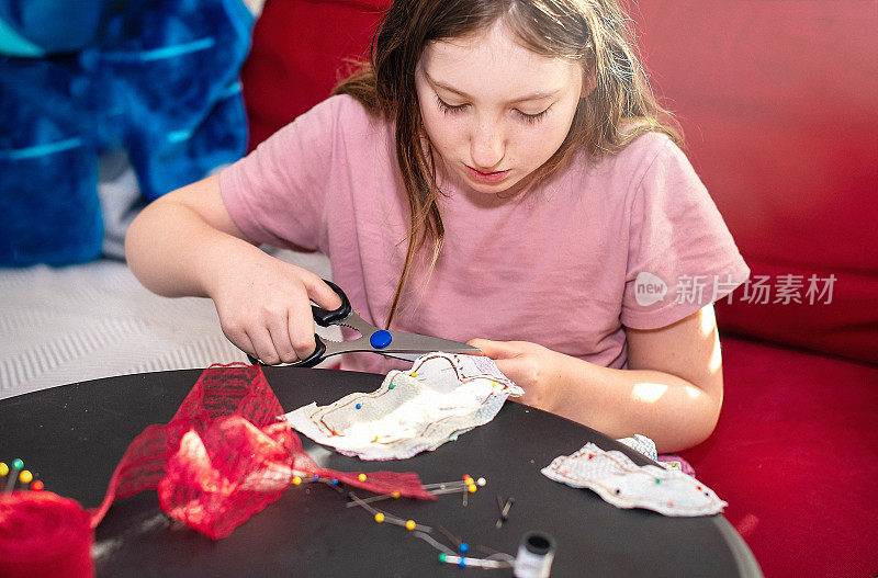 女孩正在从布料上剪出未来布料玩具的形状