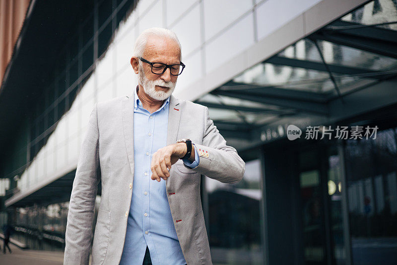 一个英俊成熟的男人走在外面，一边看手表