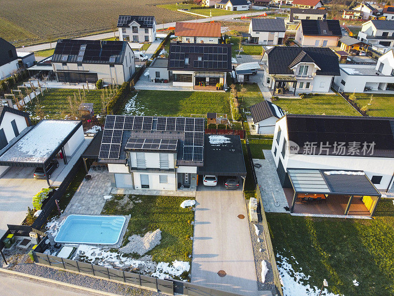 郊区住宅的鸟瞰图，有太阳能电池板，部分积雪，