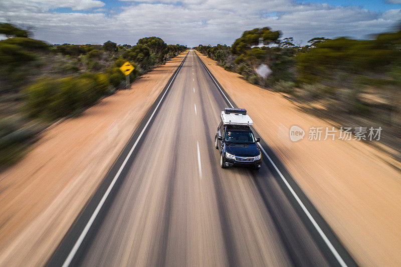 运动模糊的汽车与露营车沿着一条长而直的道路行驶在澳大利亚