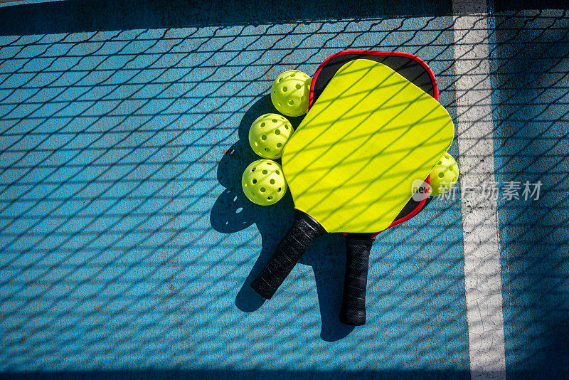 匹克球的球拍和球在有网影的匹克球场上