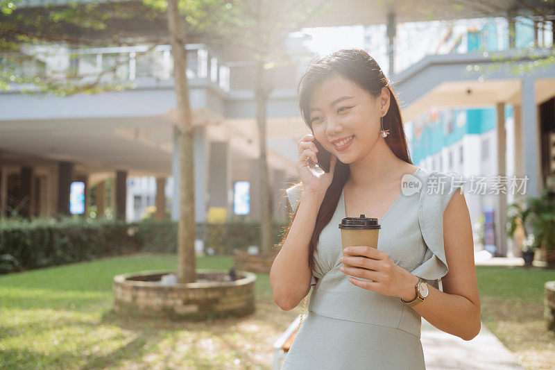 年轻时尚的亚洲女人拿着外卖咖啡和打电话