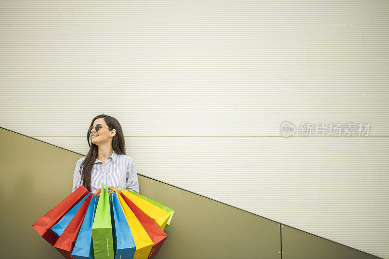 年轻快乐的女人愉快地微笑着她的购物袋孤立在灰色背景与副本空间