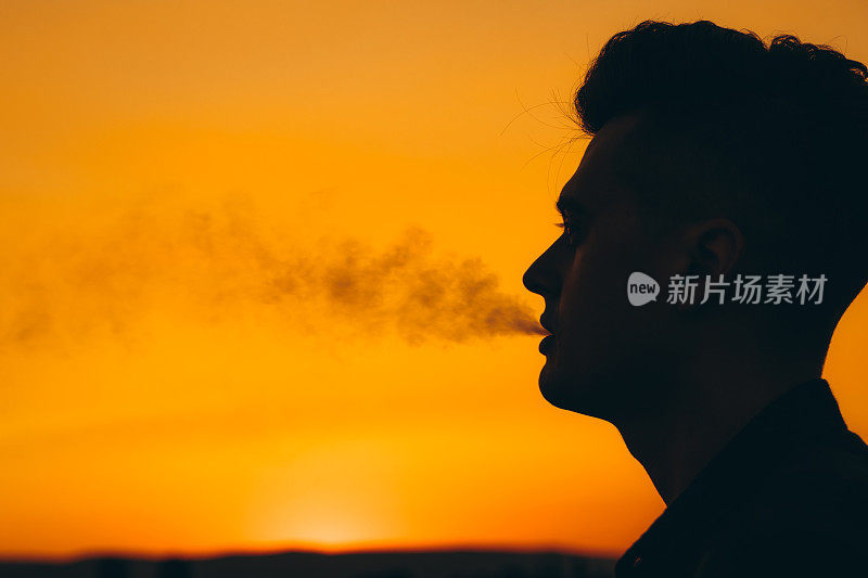 夕阳西下时，男人吐出香烟烟雾