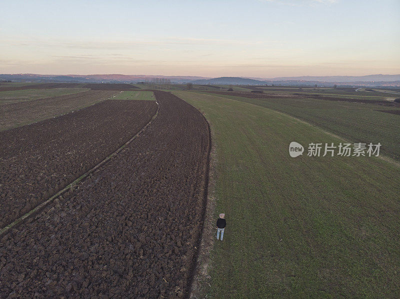 一个成年的农民在他的农场里在早春的时候耕种田地。鸟瞰图。